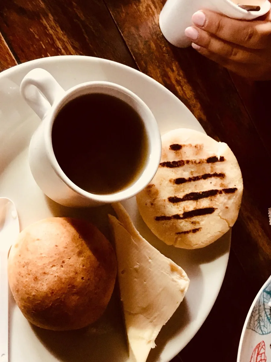 Tinto, pandebono, arepa y queso servidos en una mesa de madera